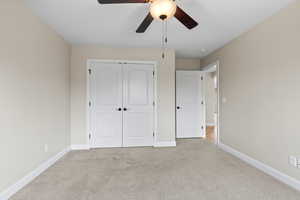 Unfurnished bedroom with light carpet, a ceiling fan, baseboards, and a closet