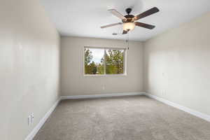 Empty room with a ceiling fan, carpet flooring, visible vents, and baseboards