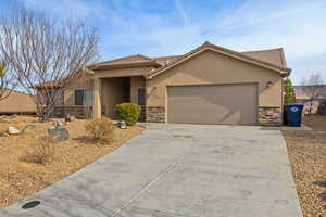 View of front of house featuring a garage, stone siding, driveway, and stucco siding