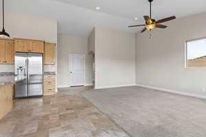 Kitchen featuring light brown cabinetry, open floor plan, stainless steel refrigerator with ice dispenser, and light stone countertops