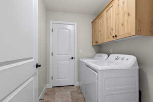 Washroom featuring baseboards, cabinet space, and washing machine and clothes dryer