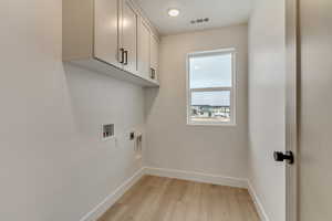 Washroom with baseboards, cabinet space, visible vents, and hookup for an electric dryer
