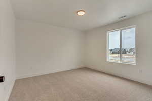 Spare room with carpet, visible vents, and baseboards