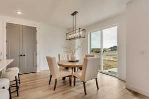 Dining area with light wood finished floors, baseboards, recessed lighting, and a chandelier