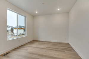 Spare room featuring light wood-type flooring, visible vents, baseboards, and recessed lighting