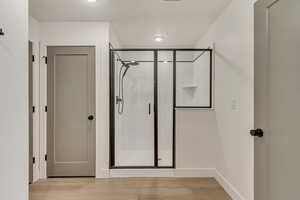 Full bathroom with a shower stall, baseboards, and wood finished floors