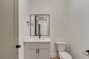 Bathroom featuring toilet, vanity, and baseboards