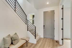 Foyer featuring stairs, light wood-style floors, baseboards, visible vents, and recessed lighting