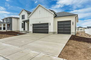 Modern farmhouse style home with board and batten siding, an attached garage, a shingled roof, and concrete driveway