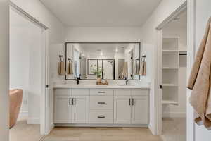 Bathroom featuring a shower stall, baseboards, a sink, and double vanity