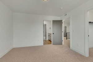 Unfurnished bedroom featuring visible vents, light carpet, a spacious closet, and baseboards