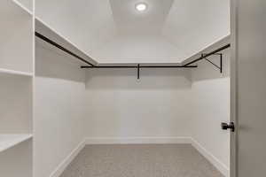 Walk in closet with lofted ceiling and carpet floors