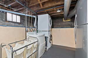 Laundry room featuring included stacked washer, dryer, and refrigerator