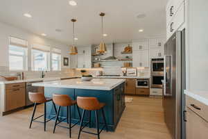 Kitchen with stainless steel appliances, a kitchen island, white cabinets, open shelves, and decorative light fixtures