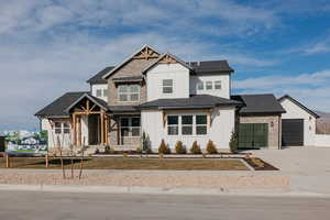 View of front facade featuring an attached garage, a shingled roof, board and batten siding, and concrete driveway