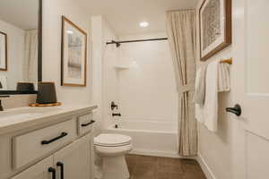 Full bath with recessed lighting, toilet, shower / bath combo with shower curtain, vanity, and baseboards