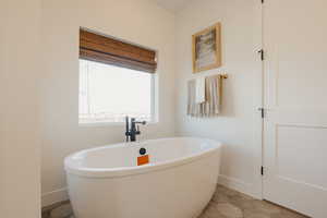 Bathroom featuring a soaking tub and baseboards