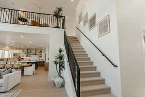 Staircase with recessed lighting, visible vents, a towering ceiling, and wood finished floors