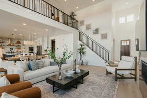 Living room with a towering ceiling, light wood-style floors, stairway, and recessed lighting