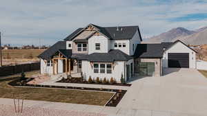 Modern farmhouse featuring a mountain view, a shingled roof, fence, concrete driveway, and board and batten siding