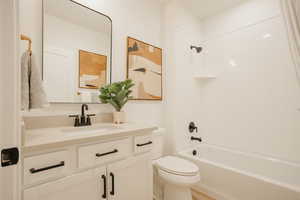 Bathroom featuring tub / shower combination, vanity, and toilet