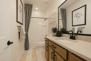 Bathroom featuring baseboards, shower / tub combo with curtain, vanity, and toilet