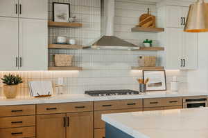 Kitchen with tasteful backsplash, white cabinets, wall chimney exhaust hood, stainless steel appliances, and open shelves