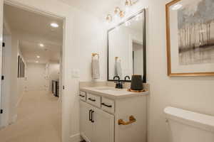 Bathroom featuring toilet, baseboards, vanity, and recessed lighting