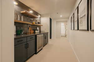 Bar with light colored carpet, beverage cooler, a dry bar, baseboards, and tasteful backsplash