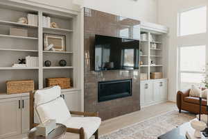 Sitting room featuring light wood finished floors, a fireplace, and built in features