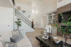 Living area featuring built in shelves, recessed lighting, stairway, a high ceiling, and light wood-style floors