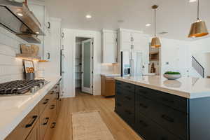 Kitchen featuring hanging light fixtures, appliances with stainless steel finishes, and white cabinets