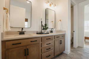 Bathroom with double vanity, a sink, toilet, and tile patterned floors