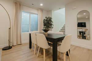 Dining area featuring visible vents, light wood finished floors, and stairs