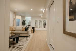 Corridor featuring light wood-style floors, recessed lighting, baseboards, and stairs