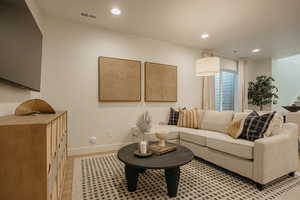 Living room featuring recessed lighting, visible vents, light wood-type flooring, baseboards, and stairs