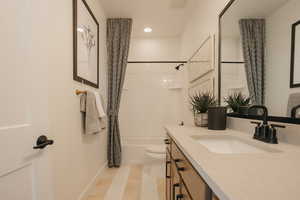 Bathroom with toilet, recessed lighting, vanity, baseboards, and shower / tub combo with curtain