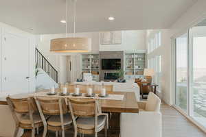 Dining area featuring light wood-style floors, recessed lighting, stairway, and a tiled fireplace