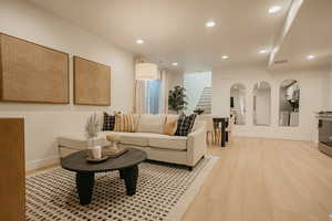 Living area with light wood-type flooring, stairs, baseboards, and recessed lighting