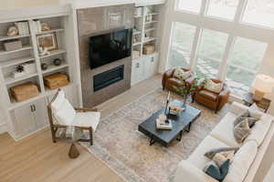 Living area featuring light wood-style floors, a tile fireplace, and built in shelves