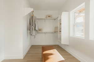 Walk in closet with light wood-style floors