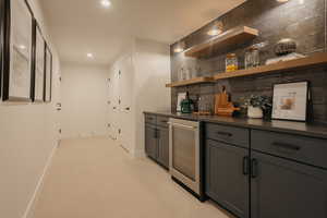 Bar with wine cooler, recessed lighting, baseboards, backsplash, and a bar