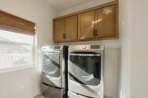 Washroom featuring washing machine and dryer, cabinet space, and baseboards