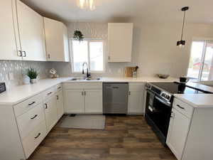 Kitchen with stainless steel appliances, light countertops, a sink, and white cabinetry