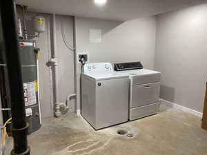 Laundry area with laundry area, secured water heater, baseboards, and separate washer and dryer