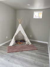 Playroom featuring a textured ceiling, baseboards, and wood finished floors