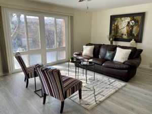 Living room with a ceiling fan, light wood-type flooring, visible vents, and baseboards