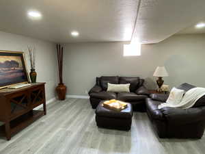 Living room featuring a textured ceiling, light wood finished floors, recessed lighting, and baseboards