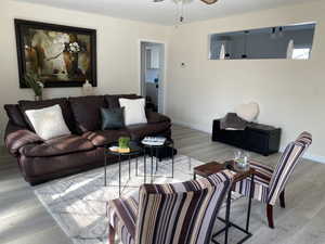 Living room with light wood-style floors, ceiling fan, and baseboards