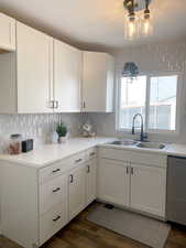 Kitchen with light countertops, a sink, and white cabinetry